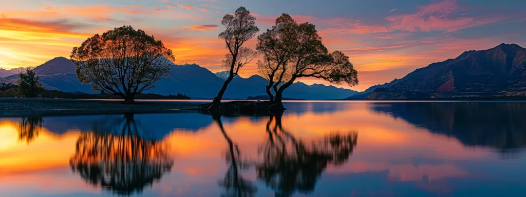 a captivating sunset casts vibrant hues over a serene lake, with silhouetted trees stretching gracefully along the shores, reflecting the stunning colours in the tranquil water.