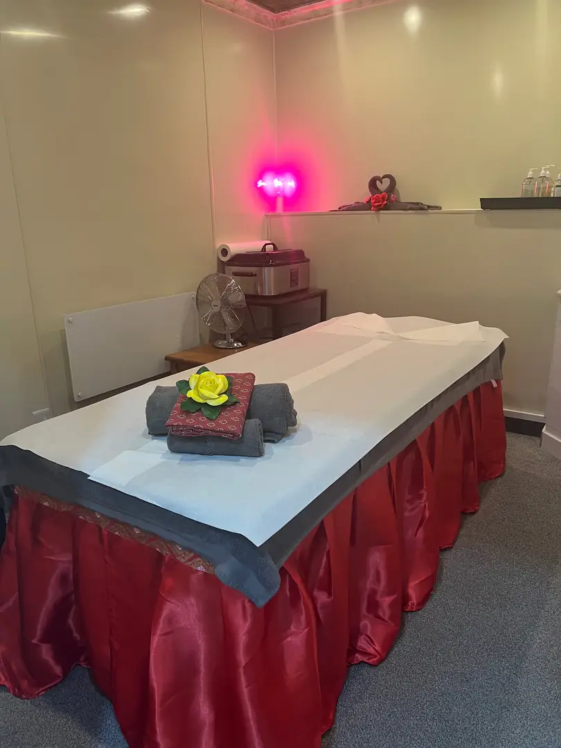 Treatment room with red satin-skirted massage table