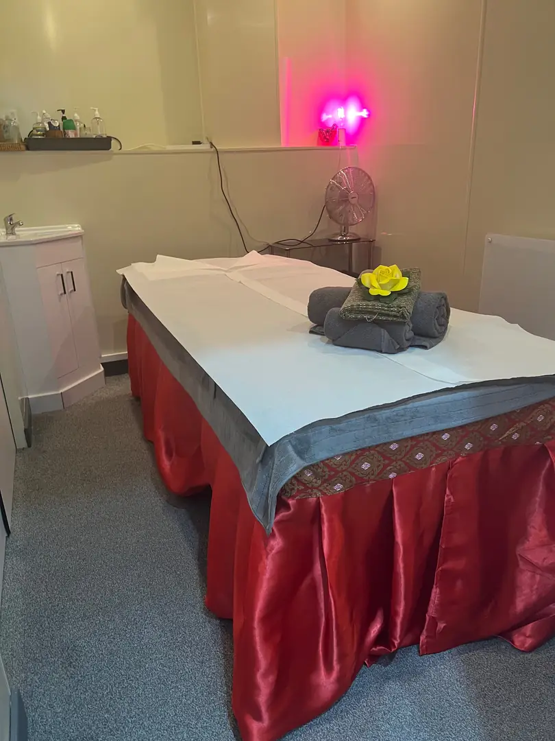 Massage table prepared with rolled towels and a flower